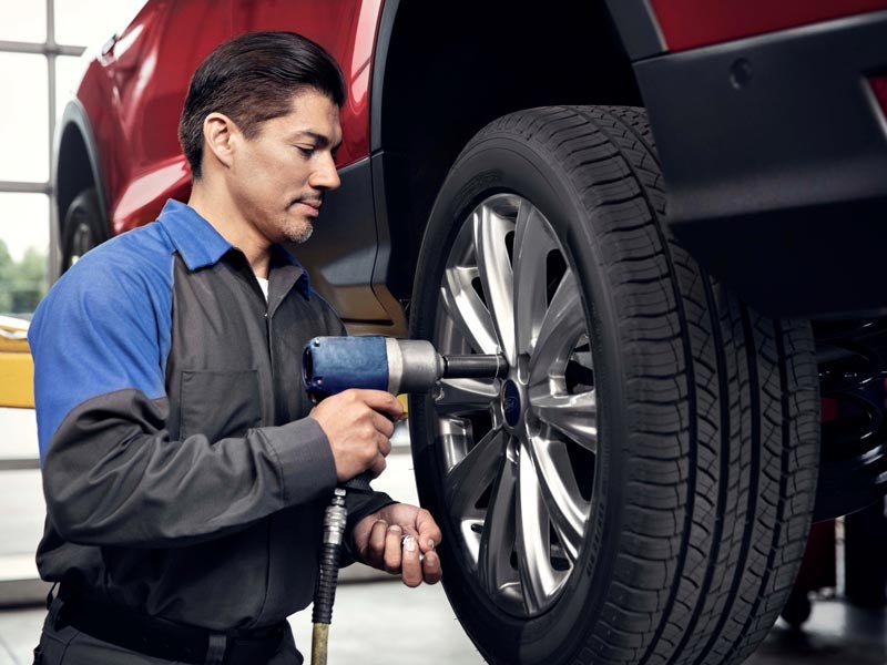 Mechanic using a power tool to tighten wheel bolts on a car in a garage